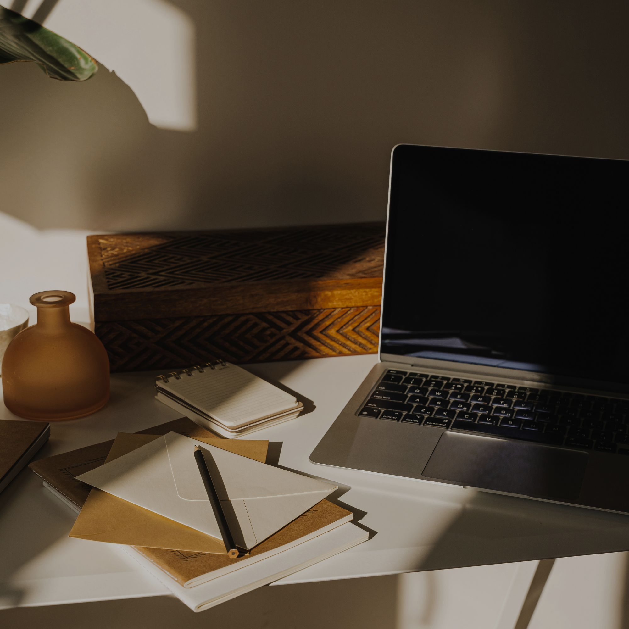Laptop on a desk with books, pen, and decorative items